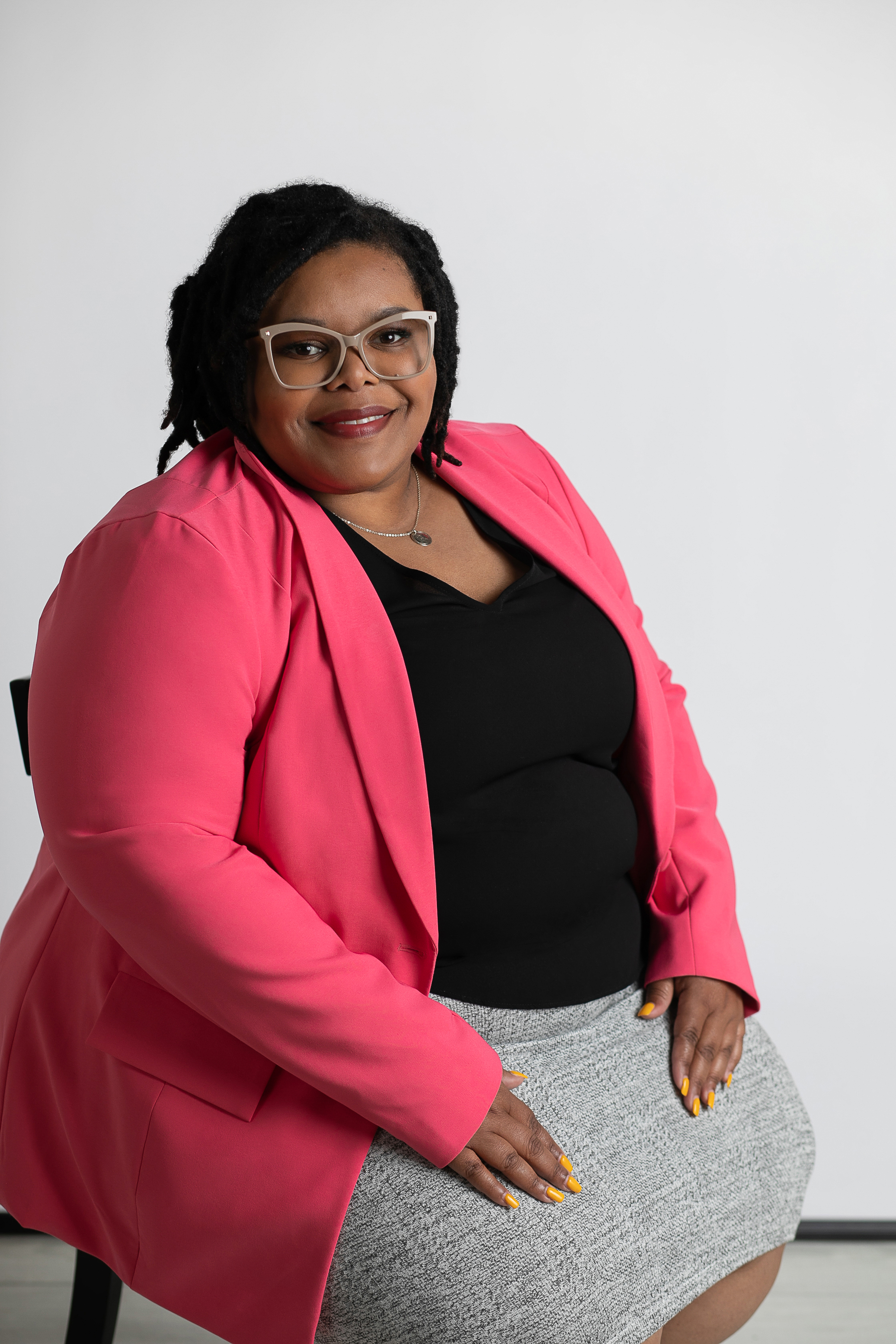 Sadé Lancaster seated in a bright pink blazer.